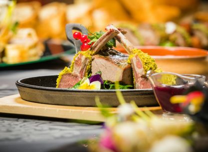 Delicious lamb chops with herb crust served with vibrant garnish and sauce.